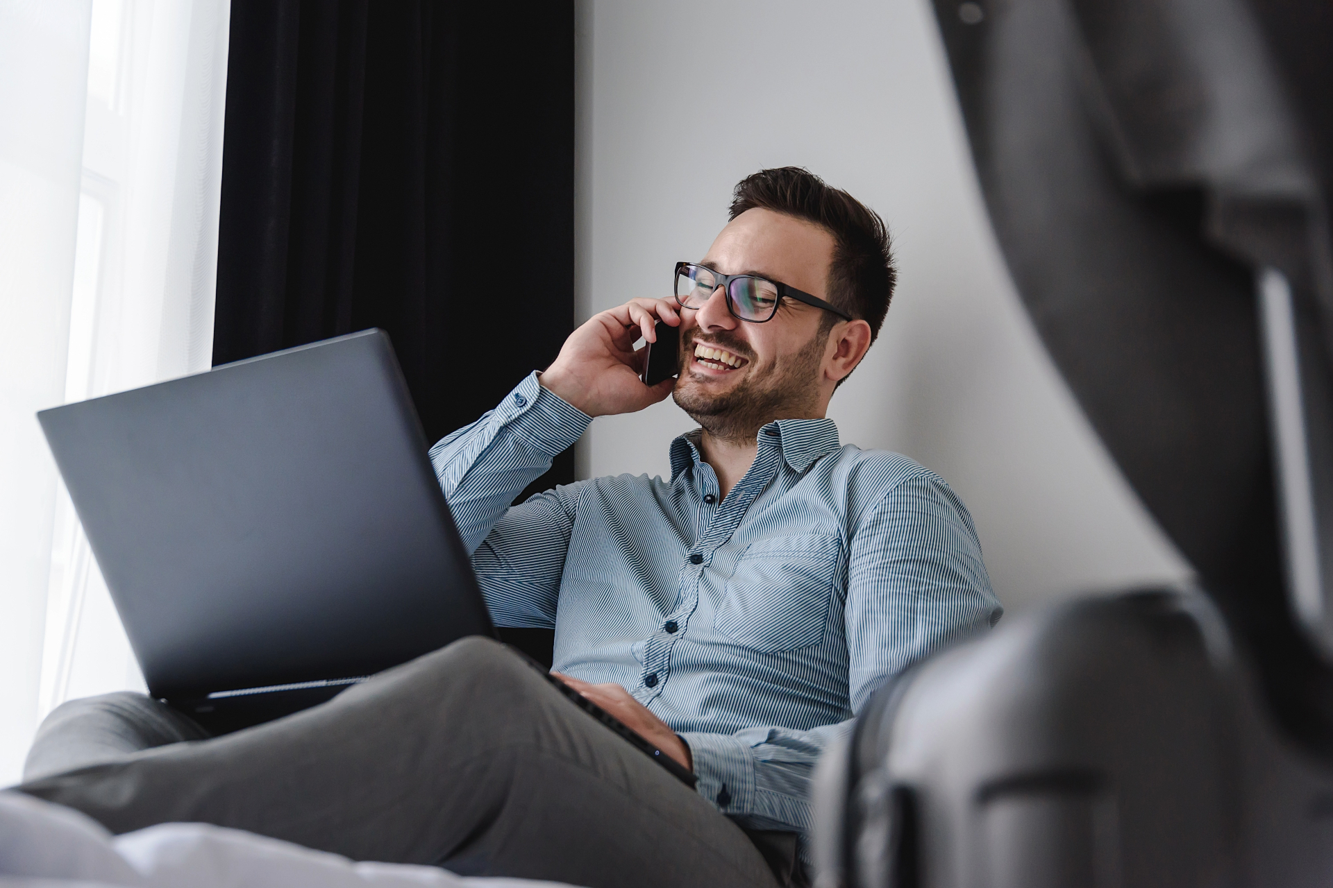 Geschäftsreisender mit Laptop und Telefon im Apartment